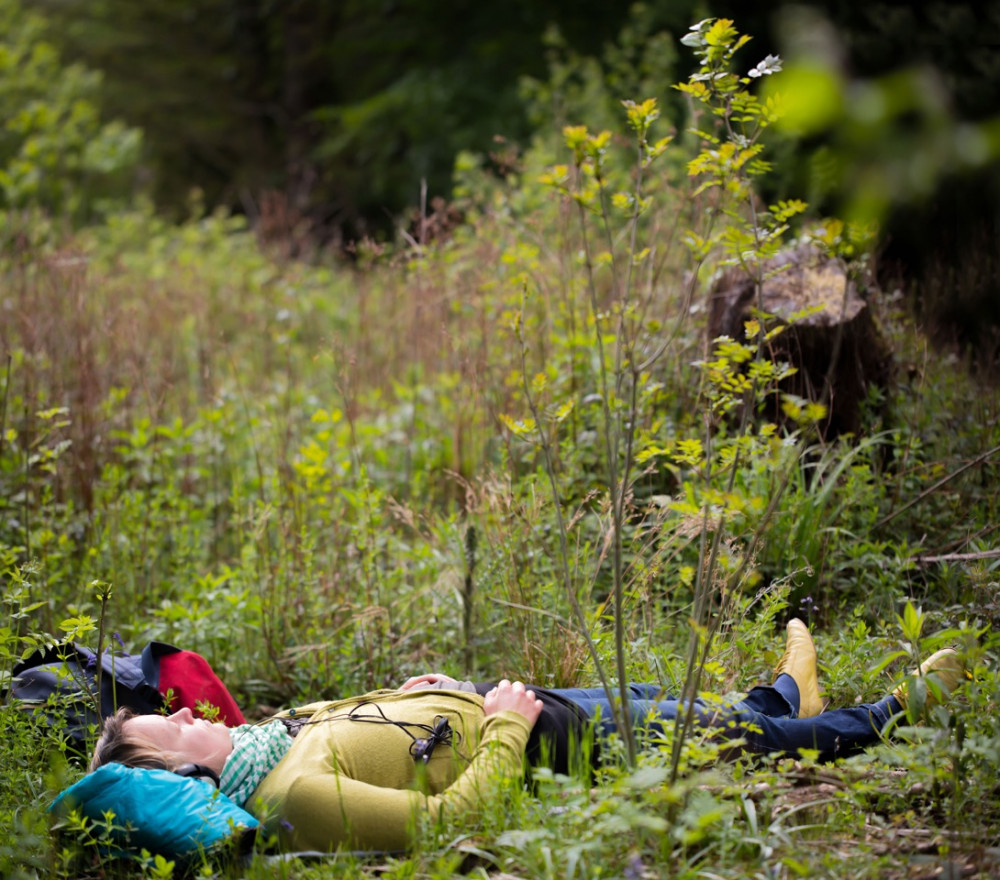 A woman laying in a filed with her eyes closed