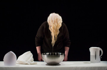 Jo has just lifted her hair out of a bowl of water, her hair drips into the bowl.