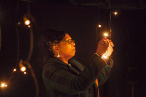 Woman looking closely at a light hung from a string in a dark room