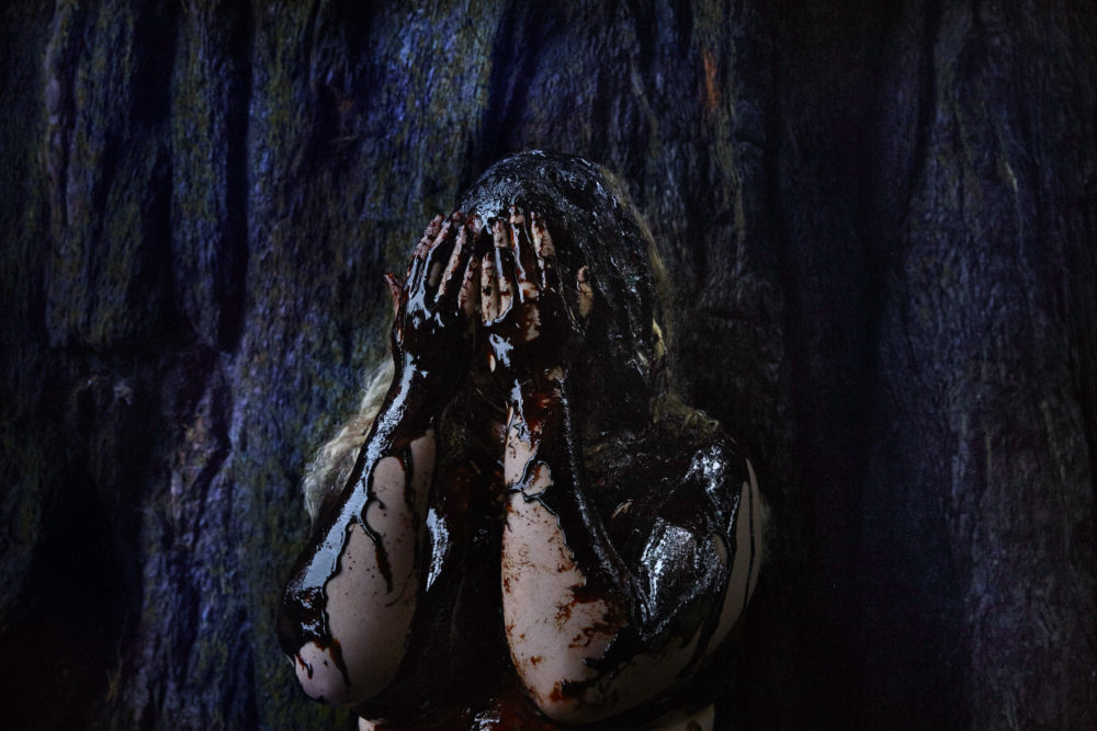 Charneh Watson, Creative Exchange Lab artist with hands over her faced covered in black liquid