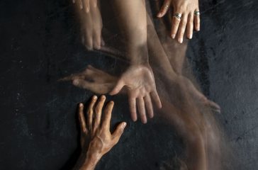 A timelapse photo of hands reaching out to each other across a black background