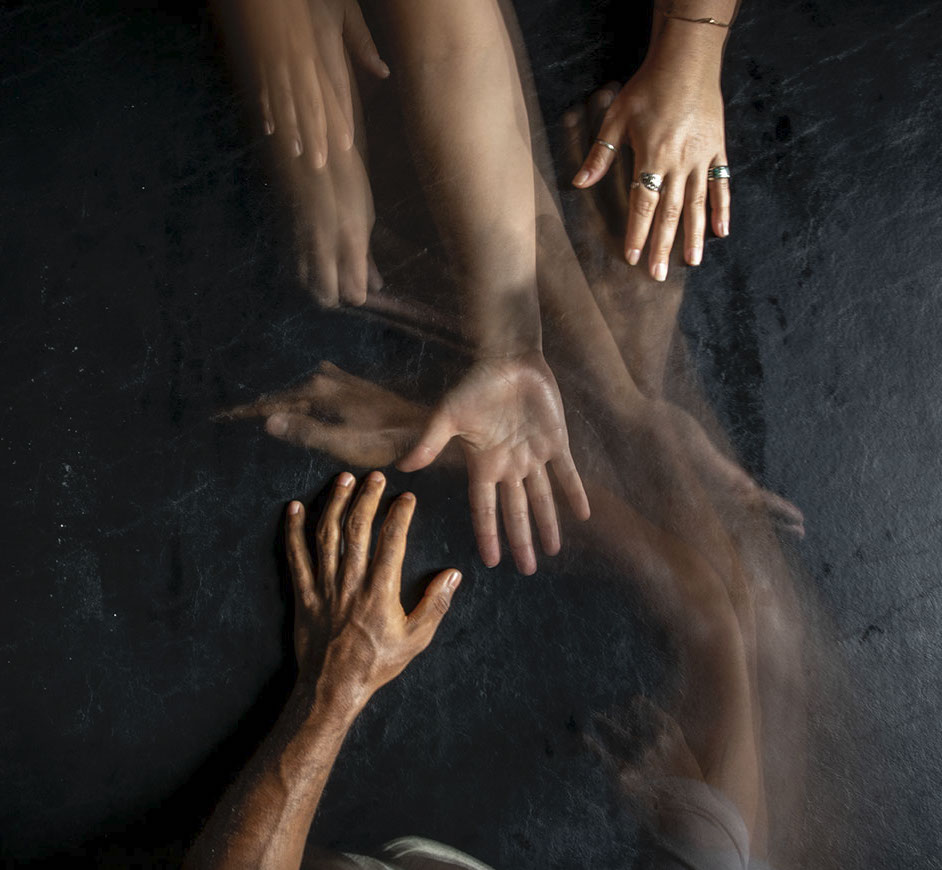 A timelapse photo of hands reaching out to each other across a black background