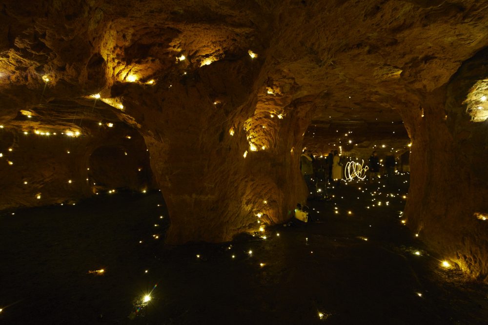 The interior of a dark cave with tiny light in the walls, roof and floor